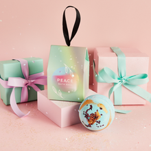 Load image into Gallery viewer, Miss Patisserie peace bath ball. Image shows the box, the unboxed bath ball, and some wrapped presents. Vegan and cruelty-free. Available at Lovethical along with plenty of other vegan and cruelty-free beauty products, makeup, make up, toiletries and cosmetics for all your gift and present needs. 

