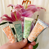 Picture of 4 different scented Fruu almighty balms being held in a person's hand in front of some flowers. Vegan and cruelty-free. Available at Lovethical along with plenty of other vegan and cruelty-free beauty products, makeup, make up, toiletries and cosmetics for all your gift and present needs. 
