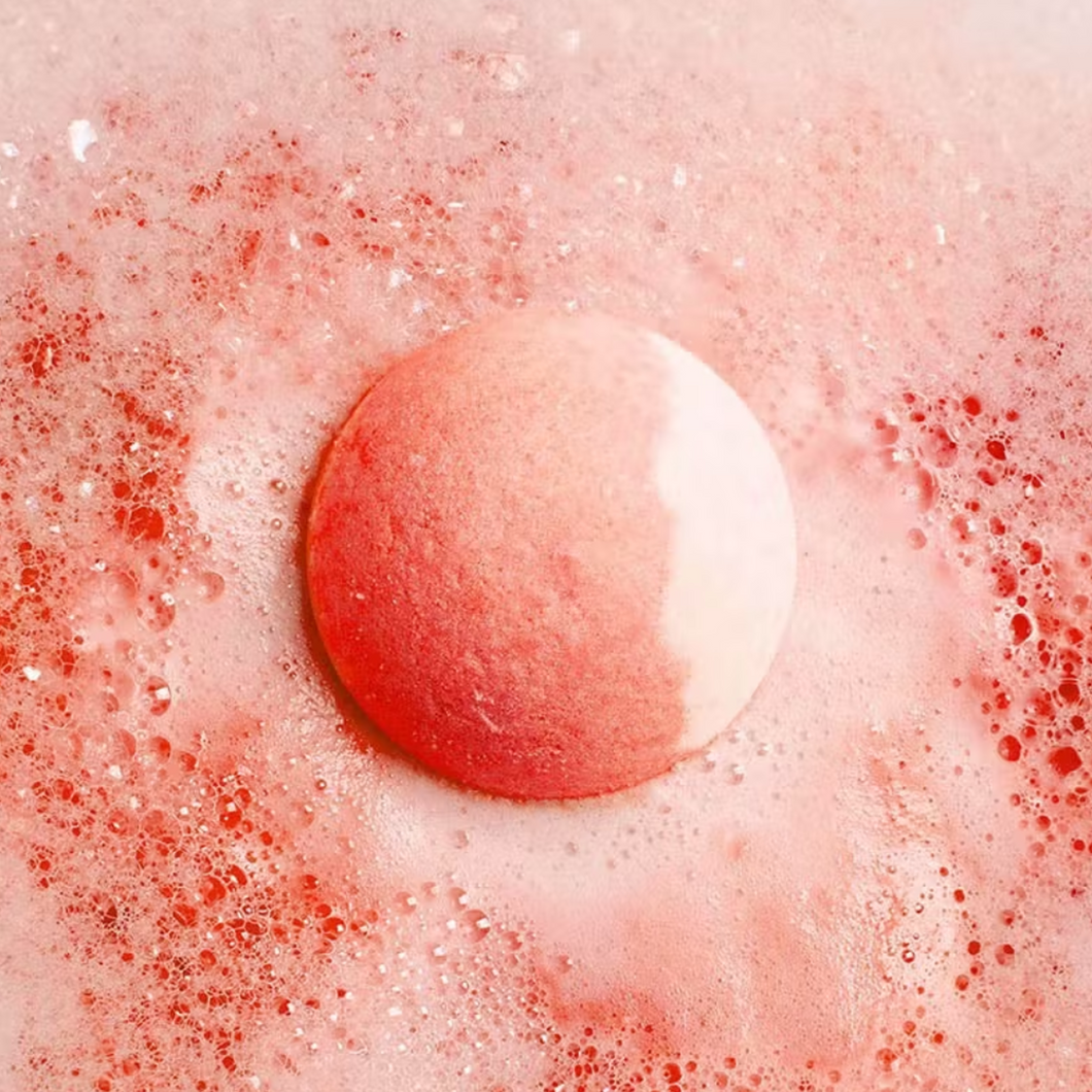 Bubble T Cosmetics peach bath bomb. Image shows the bath bomb in water surrounded by lovely peach-coloured water and bubbles. Vegan and cruelty-free. Available at Lovethical along with plenty of other vegan and cruelty-free beauty products, makeup, make up, toiletries and cosmetics for all your gift and present needs.