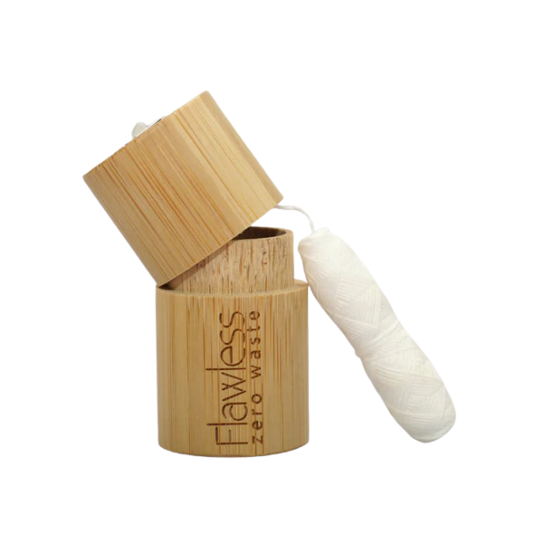 Flawless compostable dental floss with bamboo dispenser - peppermint. Image shows the bamboo dispenser and the corn fibre floss alongside it. Vegan and cruelty-free. Available at Lovethical along with plenty of other vegan and cruelty-free beauty products, makeup, make up, toiletries and cosmetics for all your gift and present needs. 