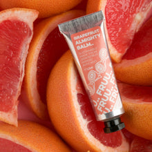 Load image into Gallery viewer, Picture of Fruu&#39;s almighty grapefruit balm in front of lots of slices of pink grapefruit. Vegan and cruelty-free. Available at Lovethical along with plenty of other vegan and cruelty-free beauty products, makeup, make up, toiletries and cosmetics for all your gift and present needs. 
