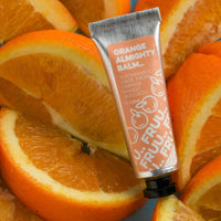 Picture of Fruu's almighty orange balm in front of lots of slices of oranges. Vegan and cruelty-free. Available at Lovethical along with plenty of other vegan and cruelty-free beauty products, makeup, make up, toiletries and cosmetics for all your gift and present needs. 