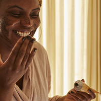 Happy and smiling woman rubbing UpCircle coffee face scrub - citrus blend - onto her face. Vegan and cruelty-free. Available at Lovethical along with plenty of other vegan and cruelty-free beauty products, makeup, make up, toiletries and cosmetics for all your gift and present needs. 