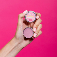 Pura Cosmetics pink tinted lip balm. Vegan and cruelty-free. Image shows a person holding the tin open and showing the vibrant pink colour within. Available at Lovethical along with plenty of other vegan and cruelty-free beauty products, makeup, make up, toiletries and cosmetics for all your gift and present needs. 