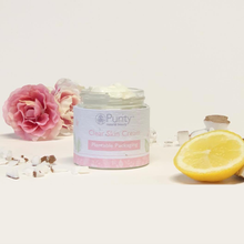 Load image into Gallery viewer, Picture of an open pot of Purity&#39;s Clear Skin Cream, with some pink flowers, pieces of coconut and some lemon arranged around it. Vegan and cruelty-free. Available at Lovethical along with plenty of other vegan and cruelty-free beauty products, makeup, make up, toiletries and cosmetics for all your gift and present needs. 

