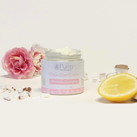 Picture of an open pot of Purity's Clear Skin Cream, with some pink flowers, pieces of coconut and some lemon arranged around it. Vegan and cruelty-free. Available at Lovethical along with plenty of other vegan and cruelty-free beauty products, makeup, make up, toiletries and cosmetics for all your gift and present needs. 