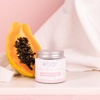 Pot of Purity's cream cleanser alongside half a papaya, with a pink background. Vegan and cruelty-free. Available at Lovethical along with plenty of other vegan and cruelty-free beauty products, makeup, make up, toiletries and cosmetics for all your gift and present needs. 
