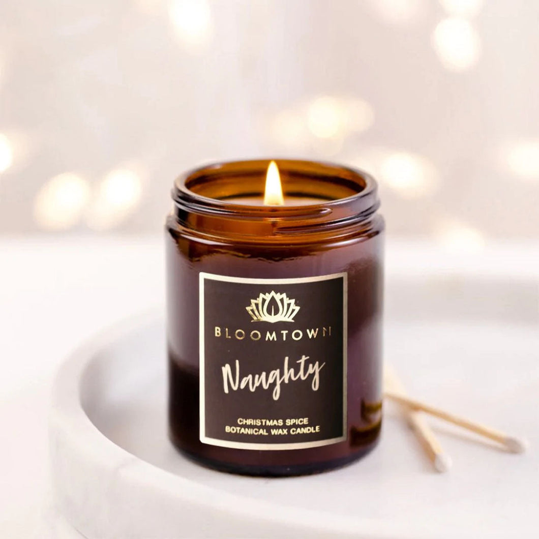 Bloomtown naughty candle - christmas spice. Vegan and cruelty-free. Image shows the lit candle. Available at Lovethical along with plenty of other vegan and cruelty-free beauty products, makeup, make up, toiletries and cosmetics for all your gift and present needs. 