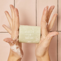 Faith in Nature soap bar. Image shows somebody's hands covered in soap bubbles and holding the soap.
