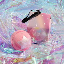 Load image into Gallery viewer, Miss Patisserie joy bath ball. Image shows the bath ball out of its box, alongside the box, with some shiny material wrapped around it. Vegan and cruelty-free. Available at Lovethical along with plenty of other vegan and cruelty-free beauty products, makeup, make up, toiletries and cosmetics for all your gift and present needs. 
