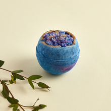 Load image into Gallery viewer, Miss Patisserie night geode bath ball. Image shows the bath bomb with some green foliage around it. Vegan and cruelty-free. Available at Lovethical along with plenty of other vegan and cruelty-free beauty products, makeup, make up, toiletries and cosmetics for all your gift and present needs. 

